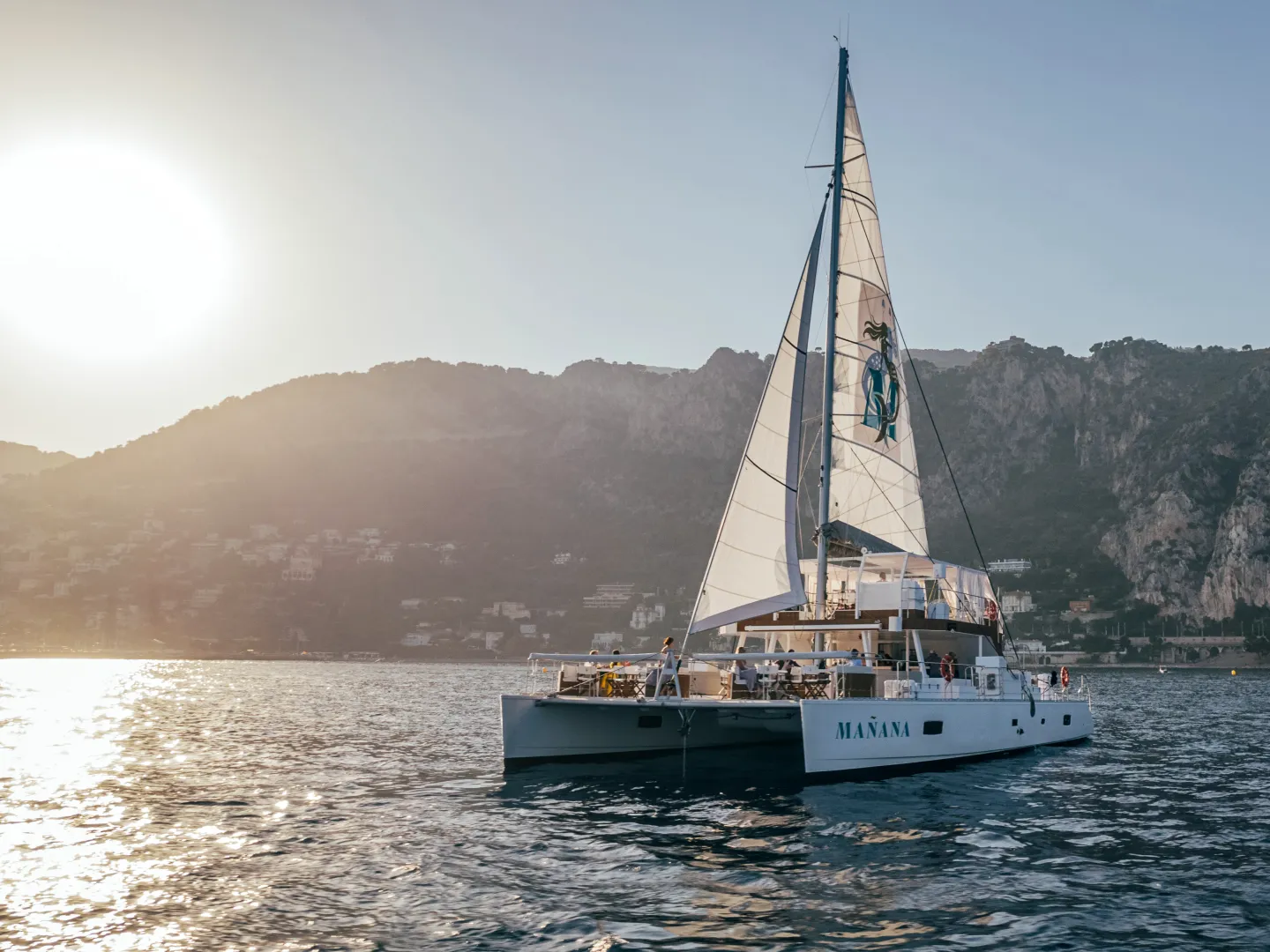 Luxury catamaran yacht Mañana with sails set illuminated by the sun in the harbor of Cannes.